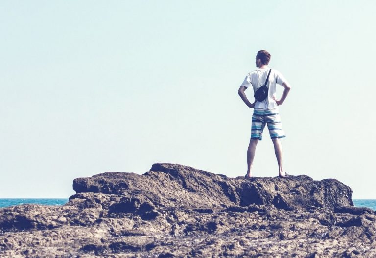 a man standing on top of a rock next to the ocean.