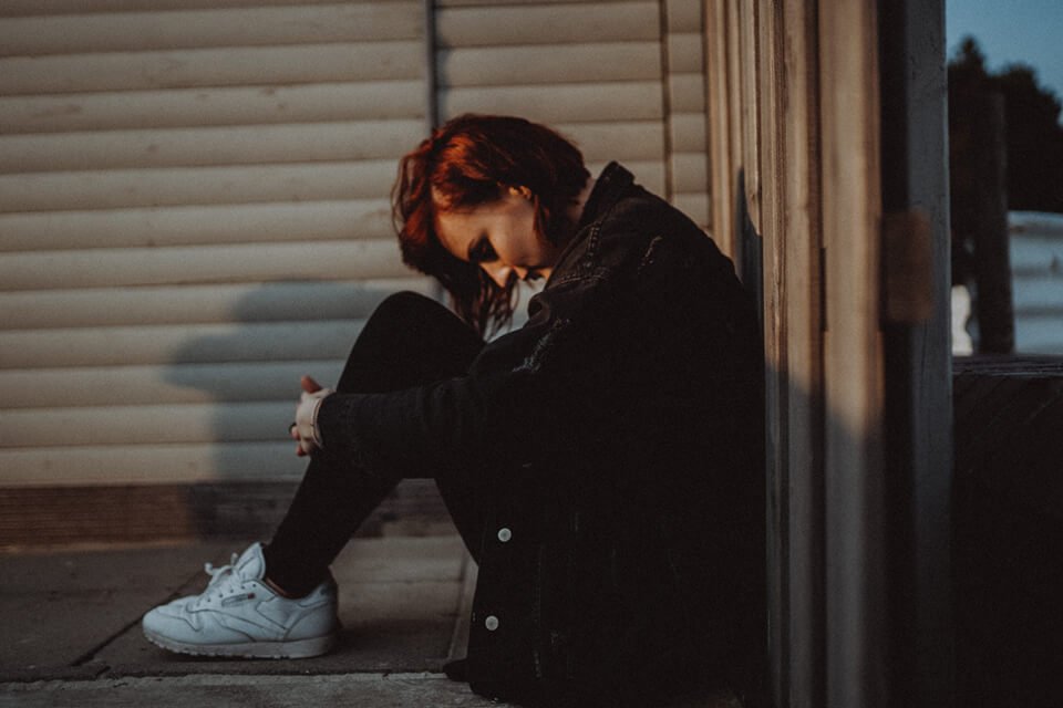 Woman crouched down lost in negative thoughts