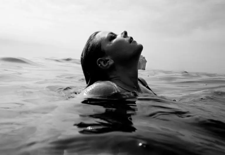 a woman floating in the ocean with her head above the water.