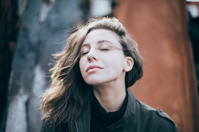 a woman with her eyes closed and her hair blowing in the wind.