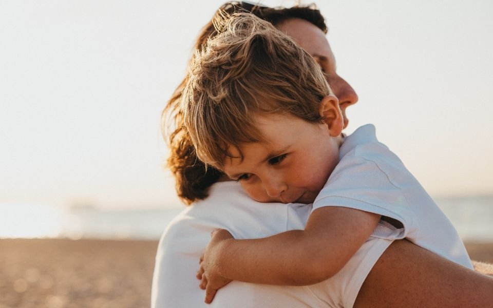 a woman holding a small child on the beach.