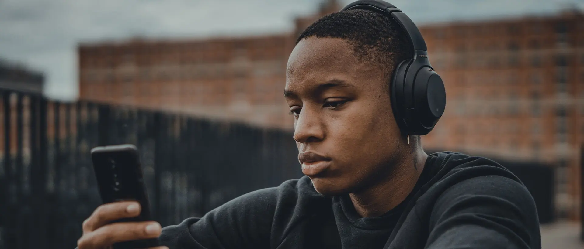 a man wearing headphones looking at his phone.