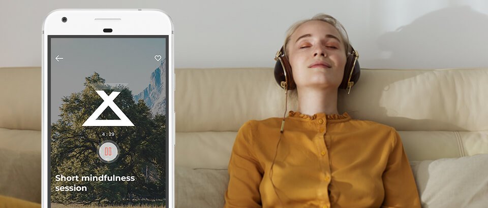 a woman laying on a couch listening to headphones.