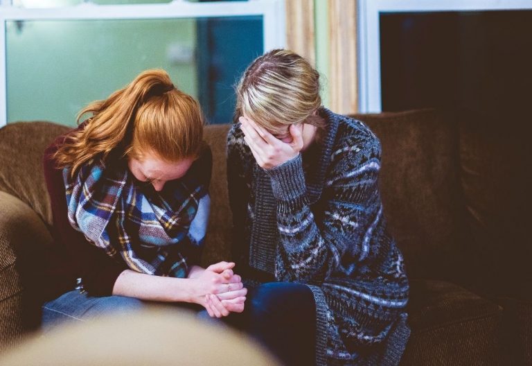 a couple of women sitting on top of a couch.