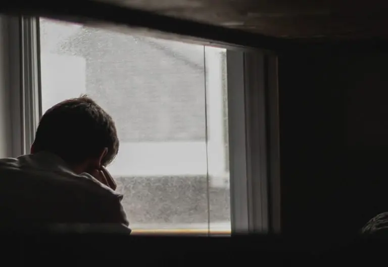 a person standing in front of a window talking on a cell phone.