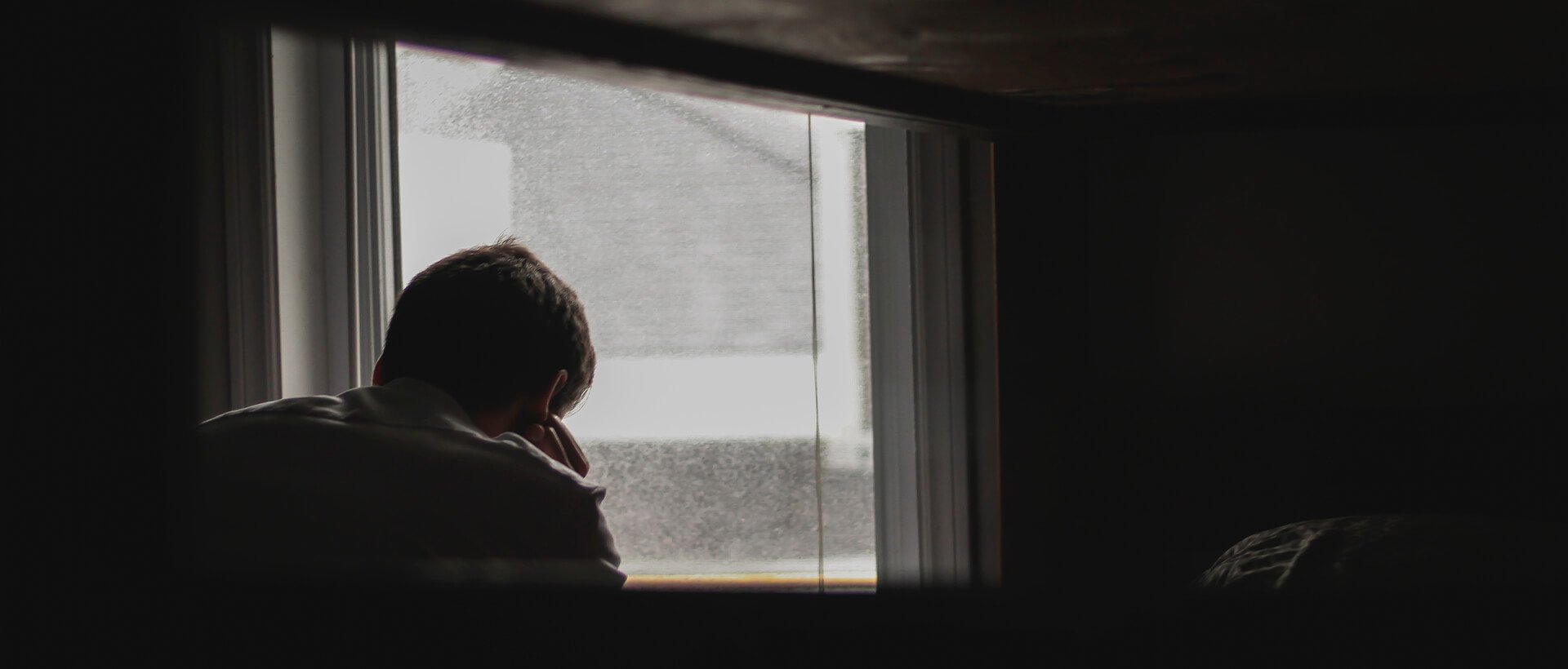 a person standing in front of a window talking on a cell phone.