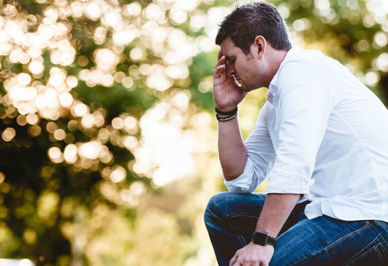 a man sitting on a rock talking on a cell phone.