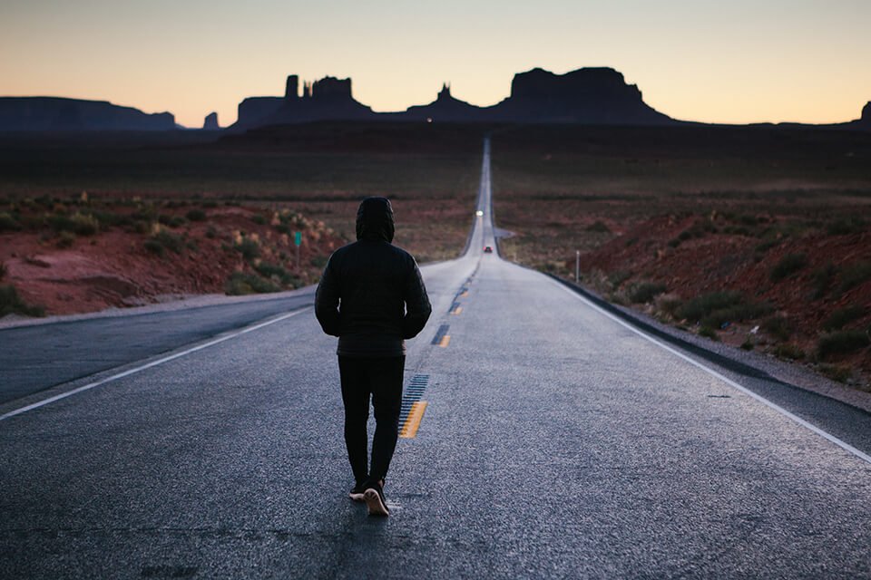 Man walking down an empty road with his hoodie on