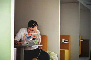 a man sitting at a table using a laptop computer.