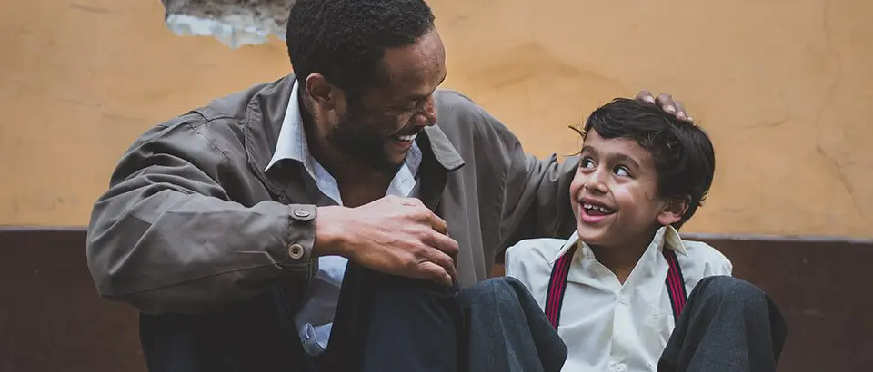 a man helping a boy put on his tie.