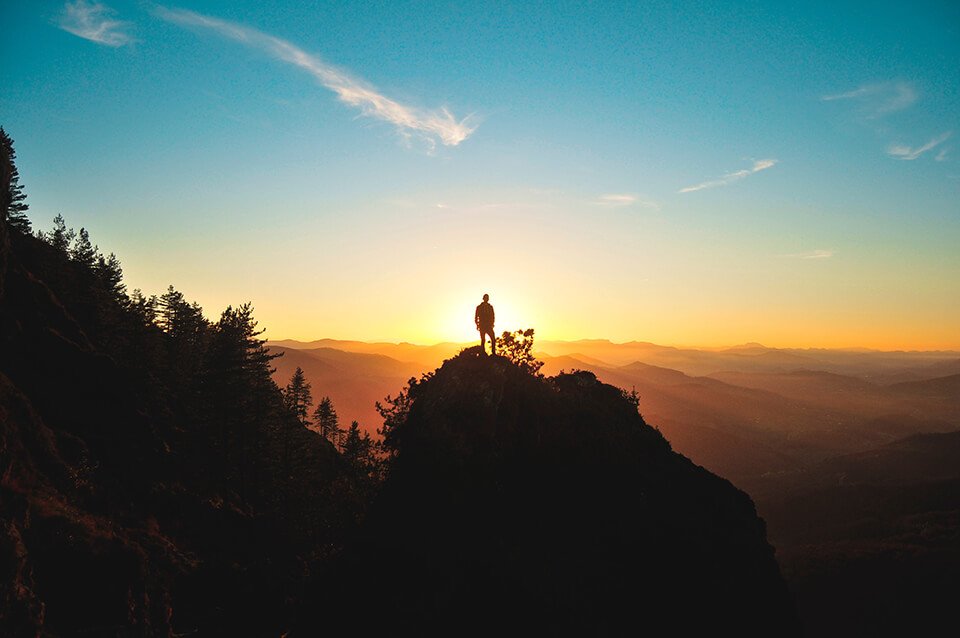 Man looking at sunset from top of hill