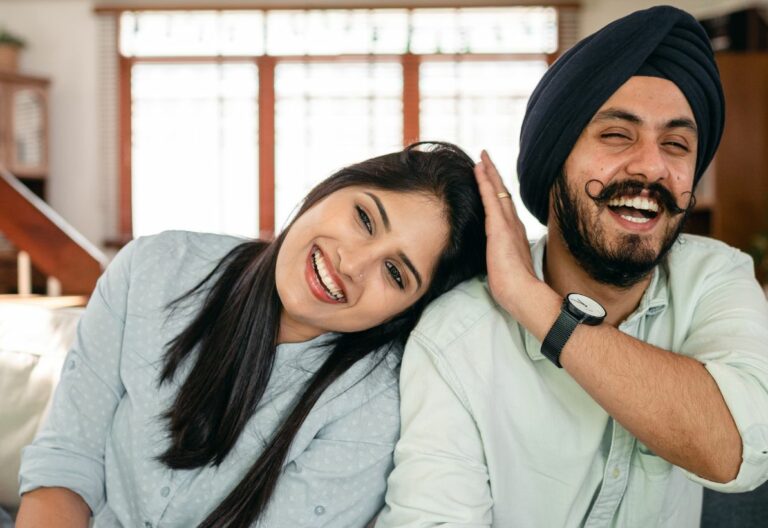 a man and a woman sitting on a couch smiling.