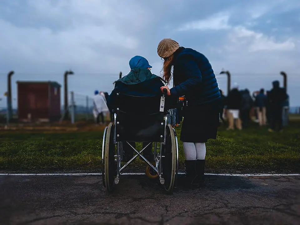 Woman helping out elderly man in wheelchair