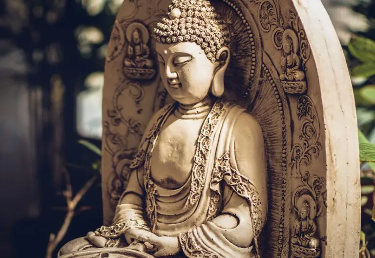 a statue of a buddha sitting in a garden.