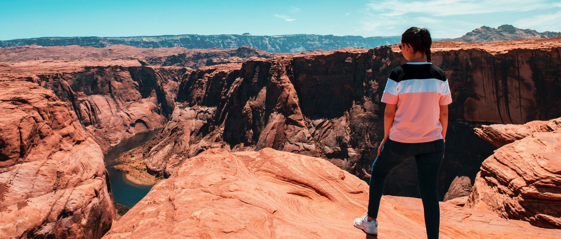 a woman standing on top of a cliff overlooking a canyon.