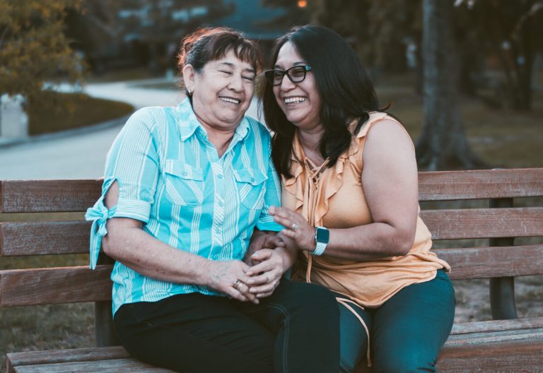 a man and a woman sitting on a wooden bench.