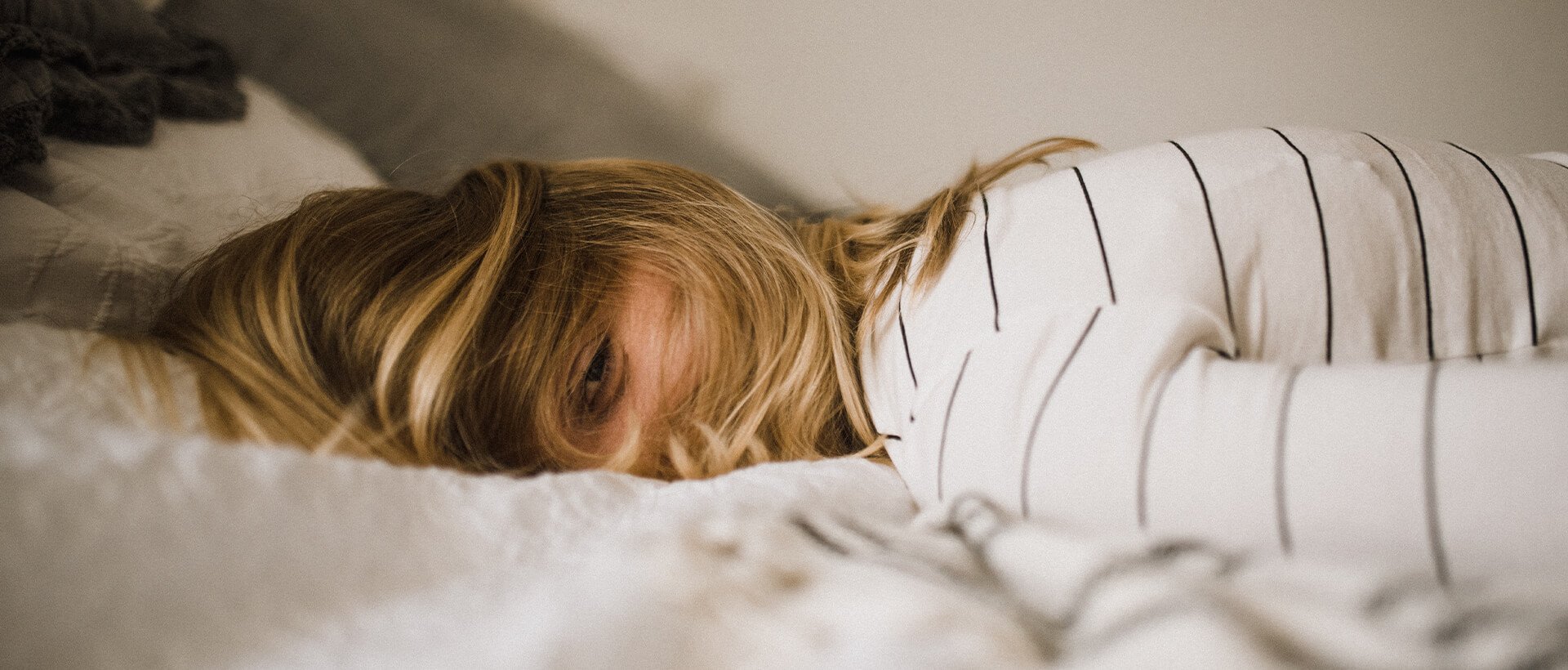 a woman laying on top of a bed under a blanket.