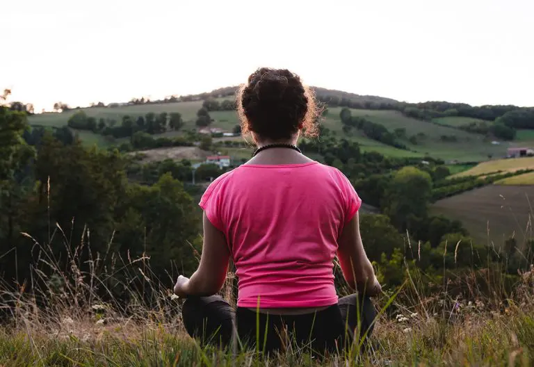 a woman in a pink shirt sitting in a field.