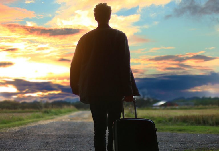 a man with a suitcase is walking out of a tunnel.