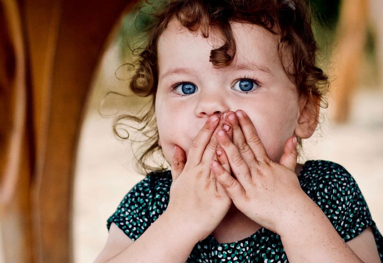 a little girl that is covering her mouth.