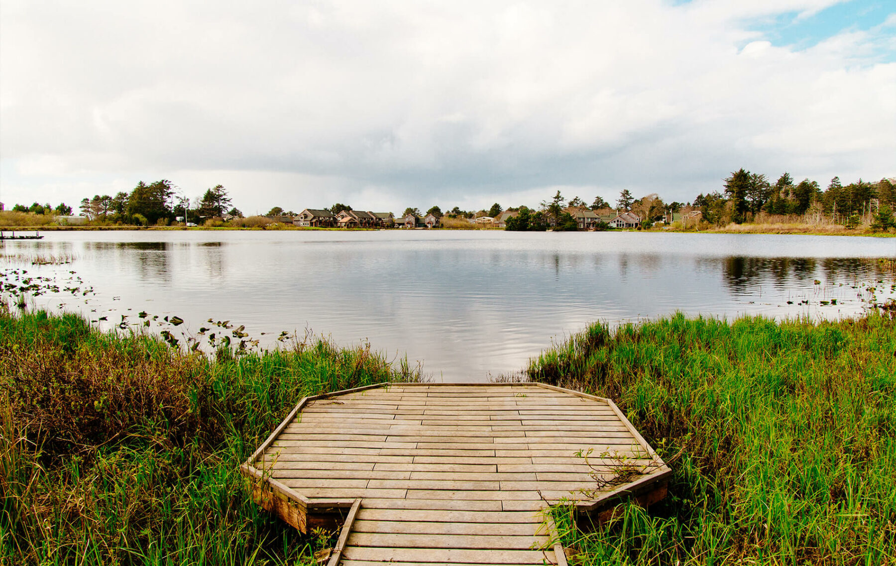 a wooden dock sitting on top of a lush green field.