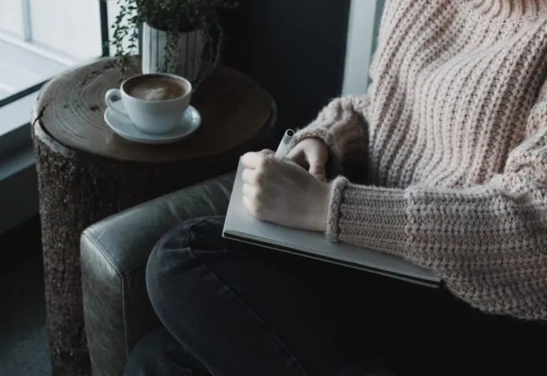 a woman sitting in a chair with a book and a cup of coffee.