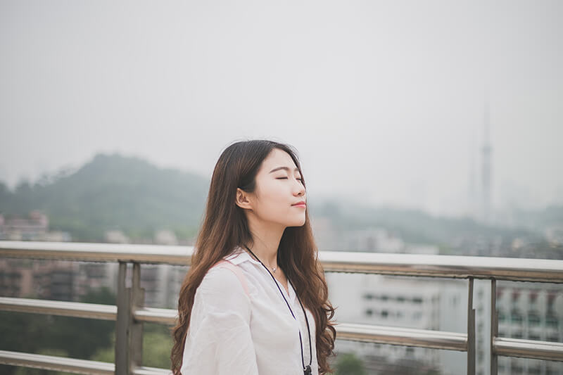 Woman sitting outside with eyes closed meditating