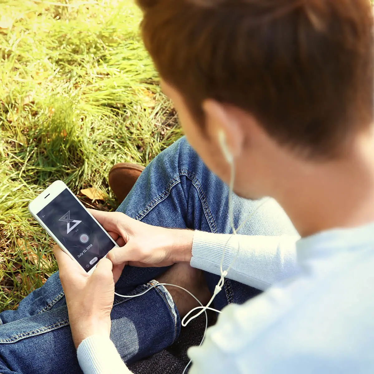 a person sitting in the grass using a cell phone.