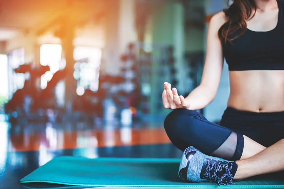 Woman sitting on yoga mat in gym meditating