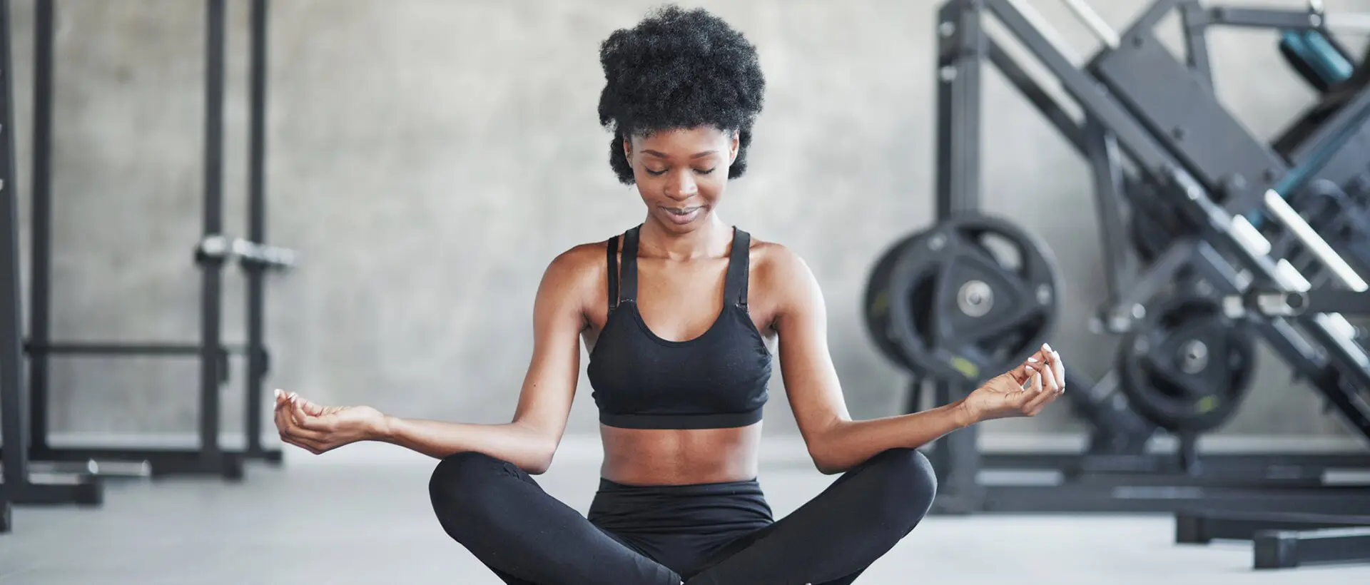 a woman sitting in a yoga position in a gym.