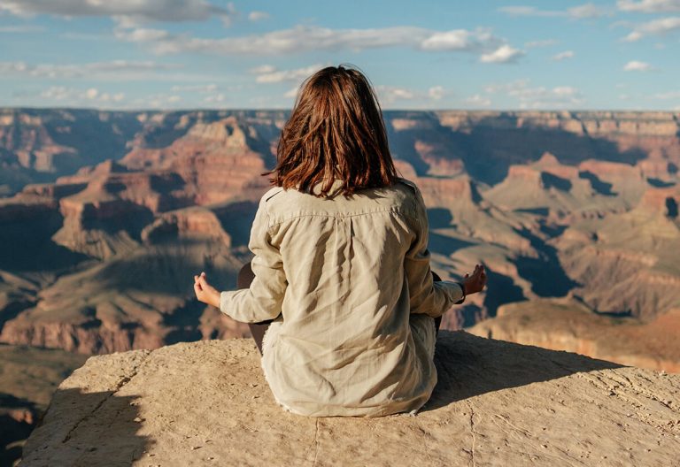 a woman sitting on top of a large cliff.