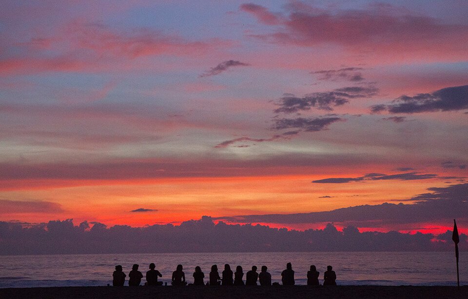 Group of people meditating by a beach