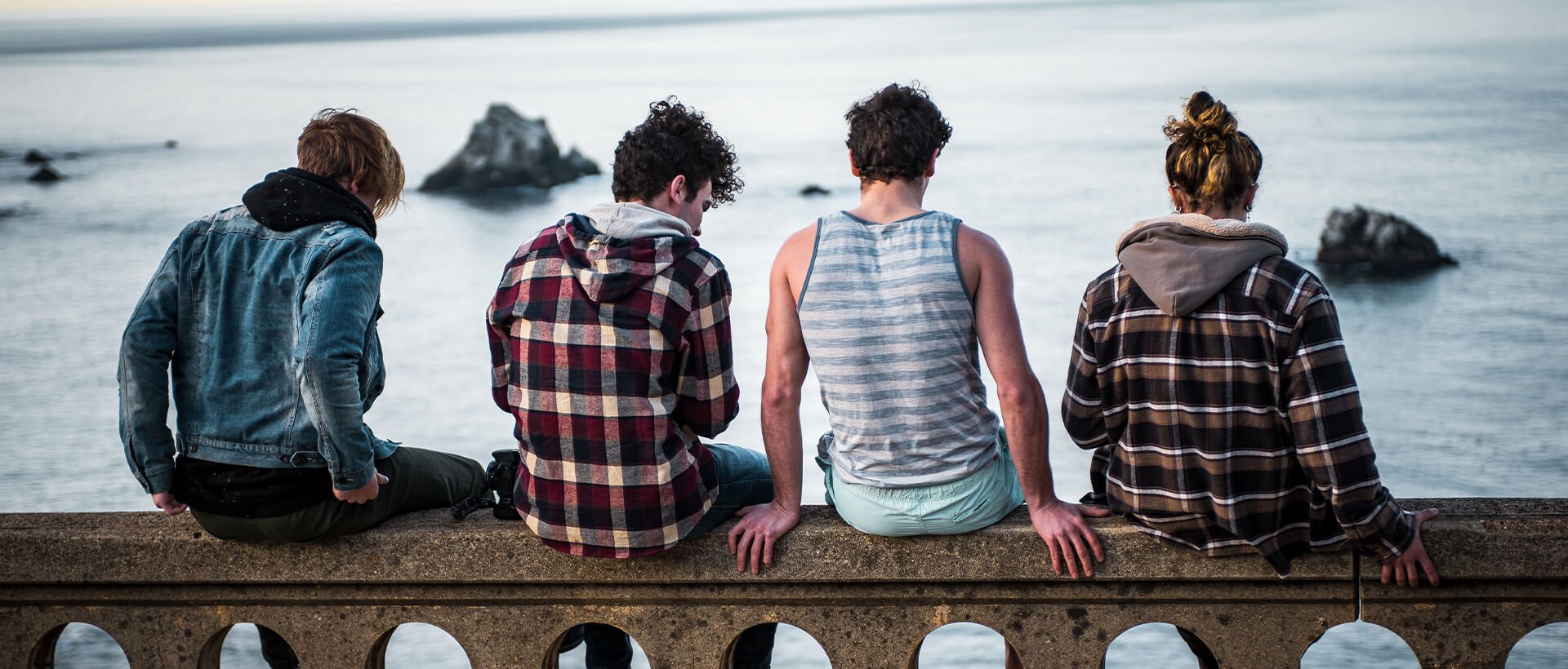 a group of people sitting on top of a stone wall.