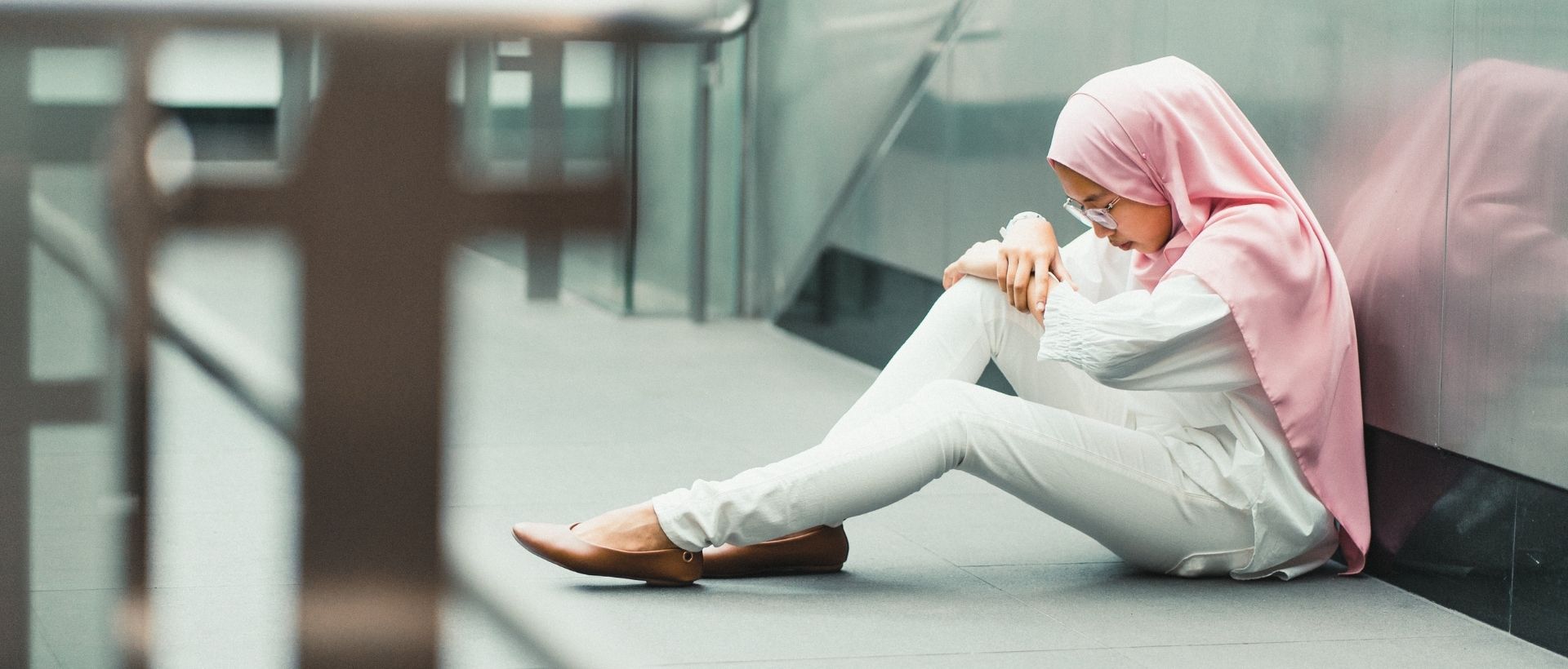 a woman sitting on the ground next to a wall.