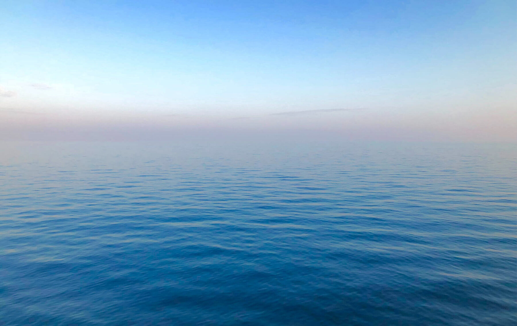 a large body of water with a sky in the background.