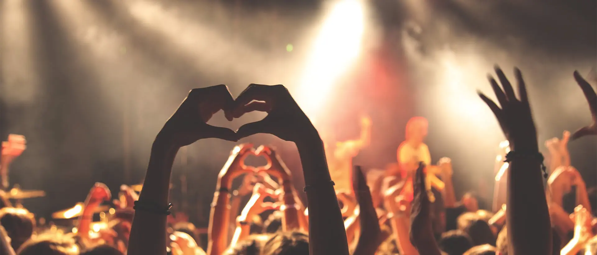 a crowd of people with their hands in the shape of a heart.