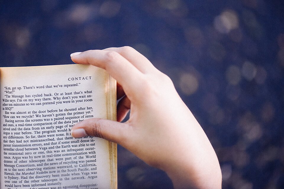 Person reading a book outdoors