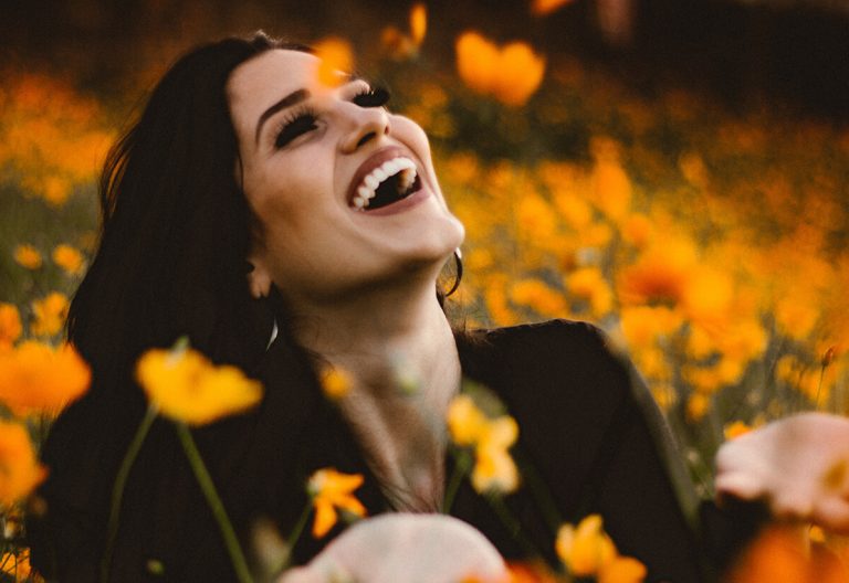 a woman laughing in a field of flowers.