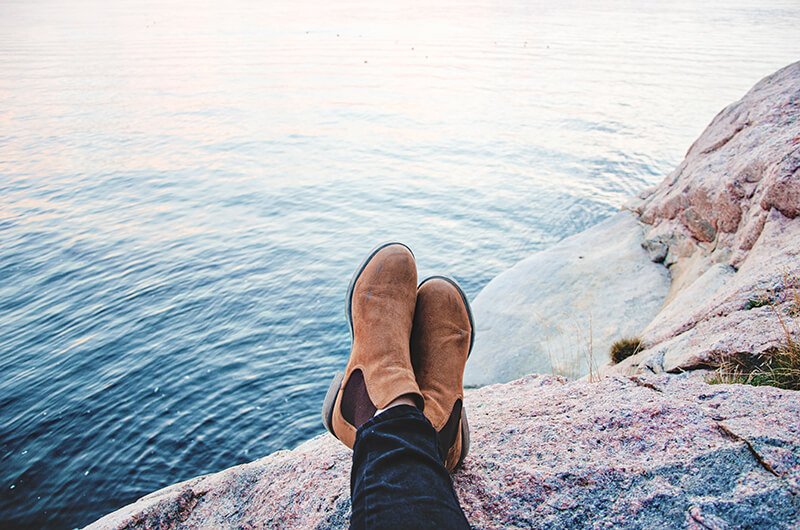 a person's feet resting on a rock overlooking a body of water.