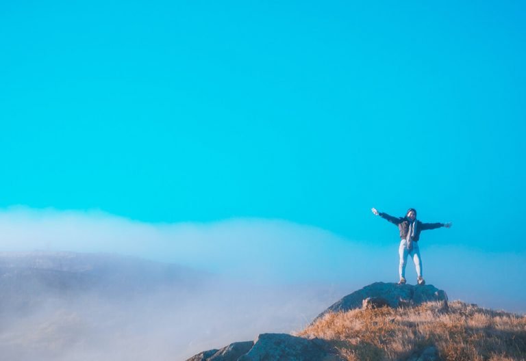 a person standing on top of a mountain with their arms outstretched.