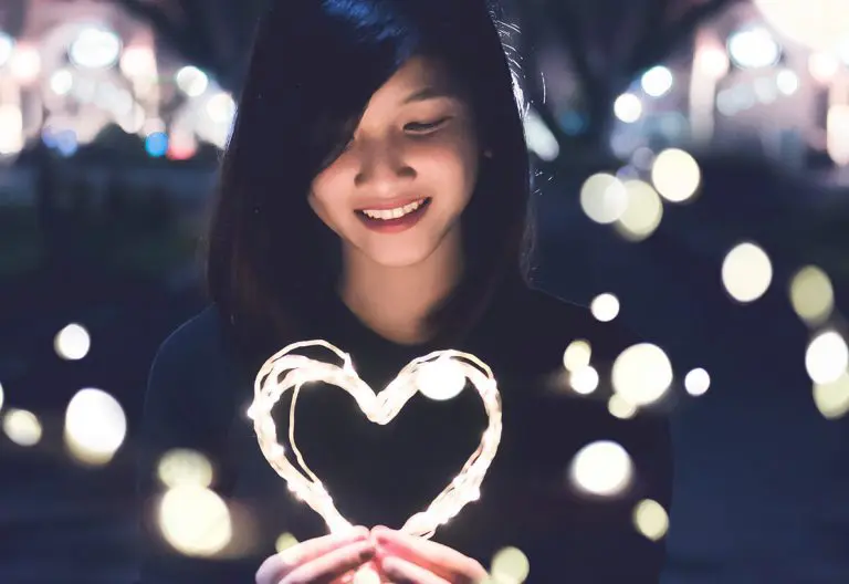 a woman holding a lit up heart in her hands.