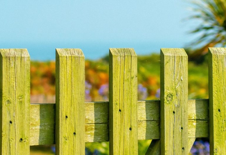 a wooden fence with a house in the background.