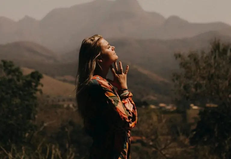 a woman standing in the mountains talking on a cell phone.