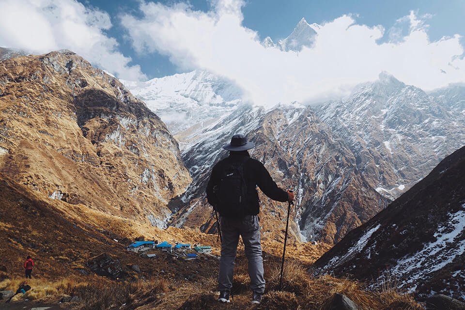 Man in hiking gear overlooking a vista from the top of a mountain