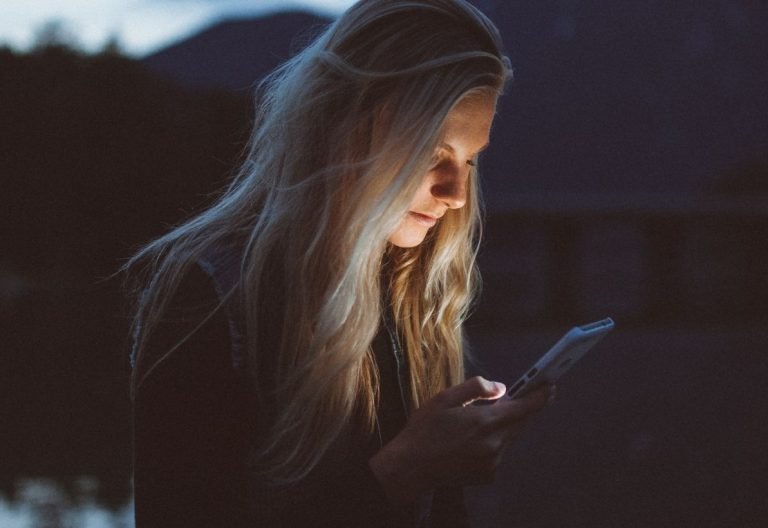 a woman looking at her cell phone in the dark.