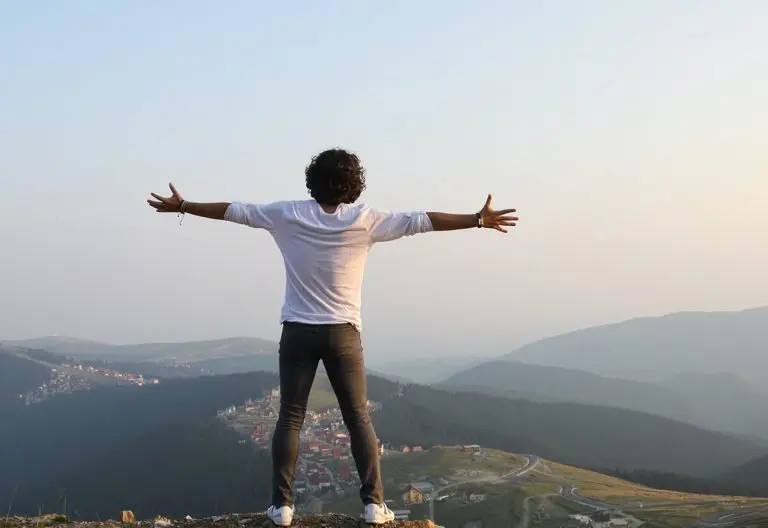 a man standing on top of a lush green hillside.