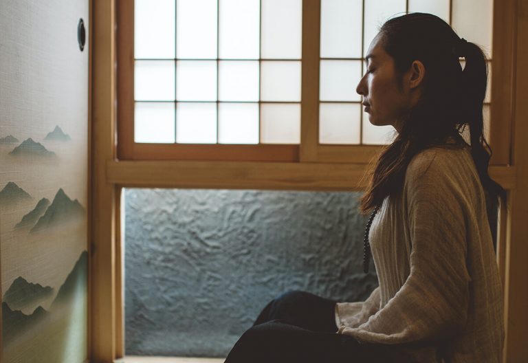 a woman sitting on the floor in front of a window.