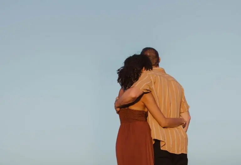 a man and a woman standing on top of a hill.