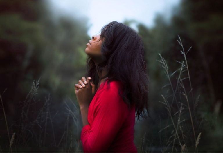 a woman in a red dress standing in tall grass.