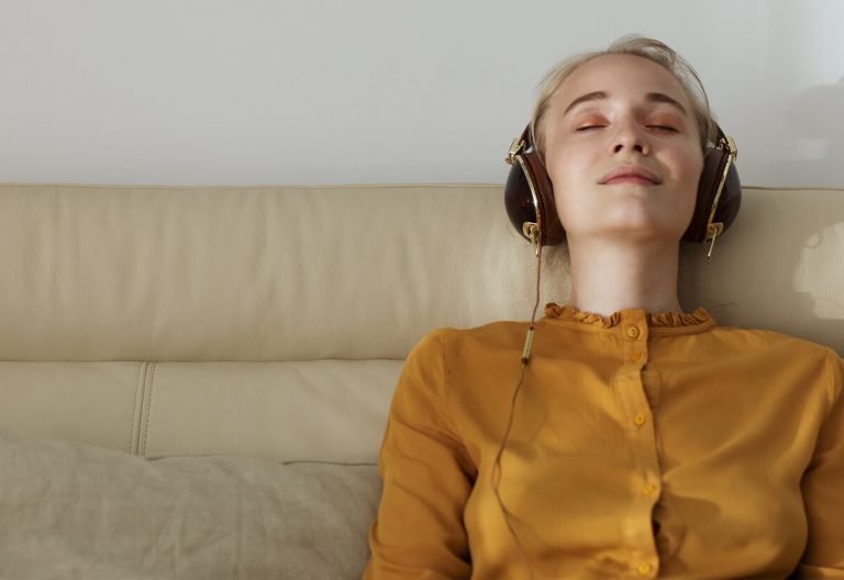 a woman wearing headphones laying on a couch.